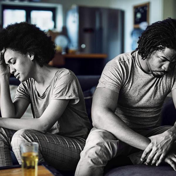 Young black couple feeling sad after arguing on sofa at home.